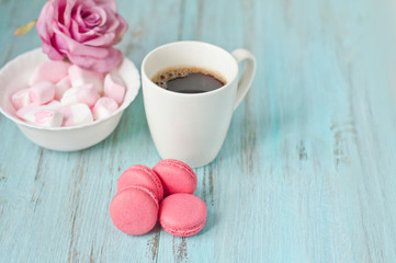 pink makkarunas, marshmallows and a cup of coffee on the table, a sweet dessert and the concept of a holiday.