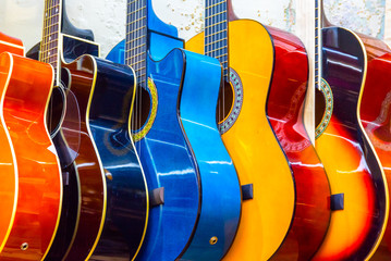 Fototapeta na wymiar colorful wooden guitars hanging on wall of store showroom