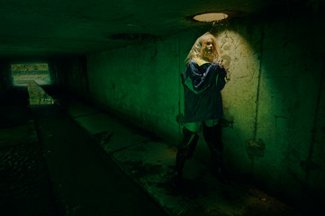 dystopian portrait of model posing in the river of sewage in tunnel under city. Lit with green light