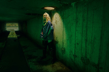 dystopian portrait of model posing in the river of sewage in tunnel under city. Lit with green light
