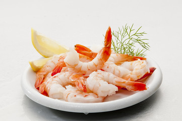 Steamed Jumbo headless shrimps with deli leaves and Lemon on white plate on white background 