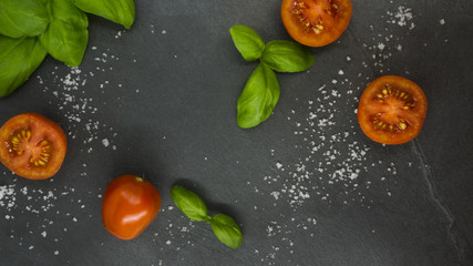 Fototapeta na wymiar Italian theme template with tomatoes and basil on a black slate