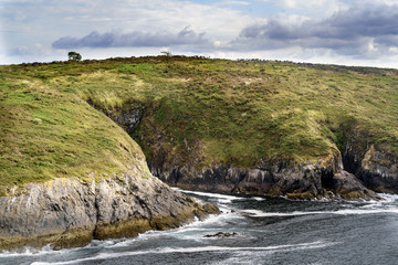 Obraz premium Vertical rocky cliffs with vegetation on the Atlantic coast of La Coruna Spainw rocky cliffs with vegetation close to the sea on the Atlantic coast