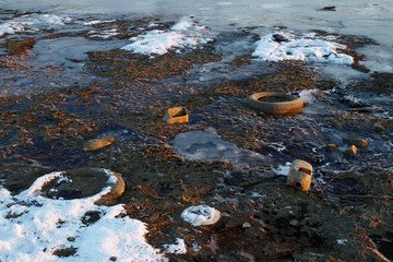 Garbage frozen in snow and mud
