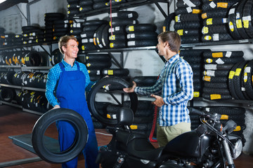 Obraz na płótnie Canvas Portrait of mechanic and customer chatting about motorbike tires