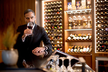 Handsome elegant businessman drinking red wine