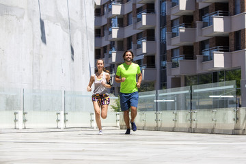 Young couple jogging for fitness in urban environment on summer day