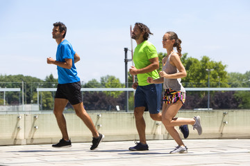 Two young men and woman running in urban enviroment