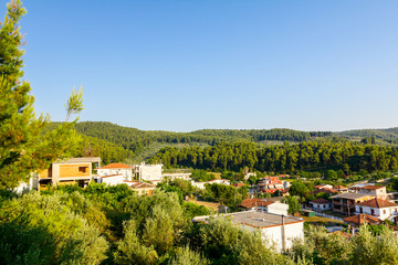 Obraz premium Settlement among hilly ground with confiner forest