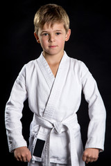 Serious kid in brand new kimono on isolated black background. Macro