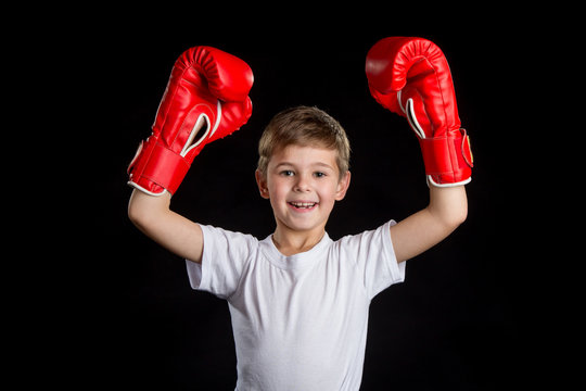 Extremely happy and successful little boxer with both hands up in red boxing gloves