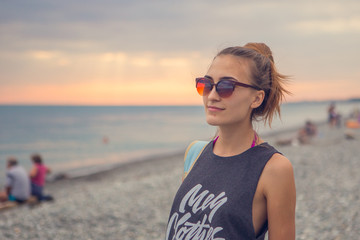 Sunset dawn. Young woman standing on a rounded pebble stones. The girl enjoys the unusual beach, pebbles on the shore of the Black sea