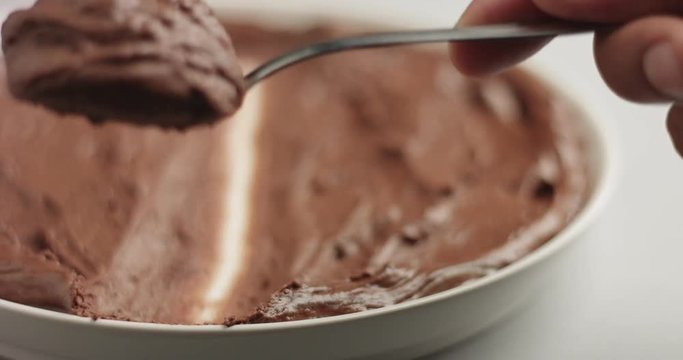 Soft spongy chocolate mousse taken out of a stainless steel pan with a teaspoon on gray background