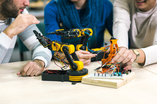 Young students of robotics preparing robot for testing in workshop