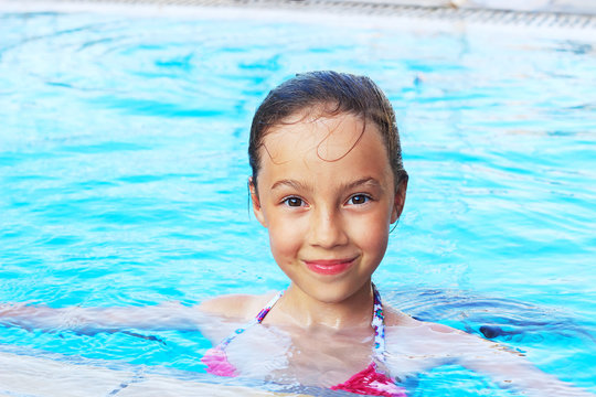 Cute little girl is smiling in swimming pool. Summer, vacation, sport concept