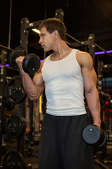 Young muscular man training dumbbells