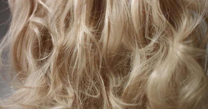 Styling long wavy blond hair with hairspray, close up shot
