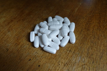 Fototapeta na wymiar Handful of white oblong calcium citrate tablets