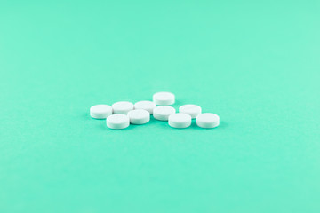 White pills with copy space on aquamarine background. Focus on foreground, soft bokeh