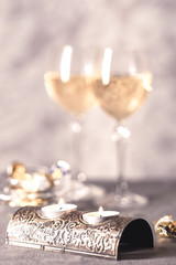 Toned shot of candles in metal candlestick on the background of two wine glasses in blur.