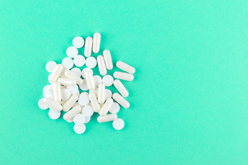 Close up white pills and capsules on aquamarine background with copy space. Focus on foreground,...
