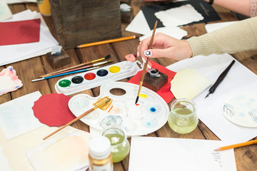 creating, arts and crafts, calligraphy concept. workplace of artist with all set of equipment for drawing such as watercolour, brushes, various pieces of paper in different colour and bottle with ink