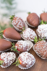 confectionary, food, cooking concept. close up of delicious dessert that is presented by strawberries that are covered with chocolate frosting and coconut shaving