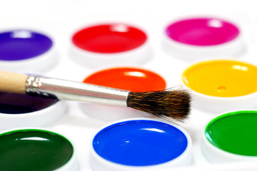 paintbrush on unused watercolor paints on white background