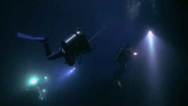 Scuba diver with flashlight on background of bottom at night underwater. Amazing unique beautiful video. Relax.