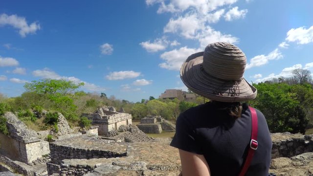 A gimbal shot of a woman sitting in mayan ruins in ek balam