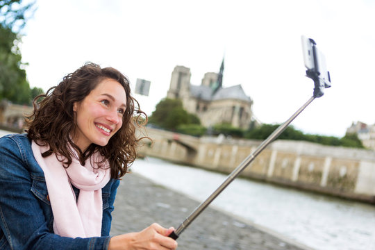 Young woman on holidays in Paris taking selfie in front on Notre Dame - Tourism concept