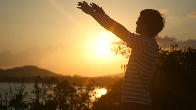 Young man wearing sunglasses raising arms to the rising sun at beautiful sunset on top of the mountain in Slow Motion. 1920x1080