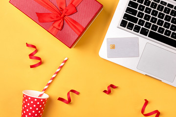 Shopping online with credit card for christmas holiday. Laptop with gifts on table on yellow background