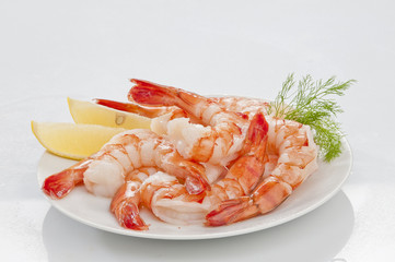 Steamed Jumbo headless shrimps with deli leaves and Lemon on white plate on white background 