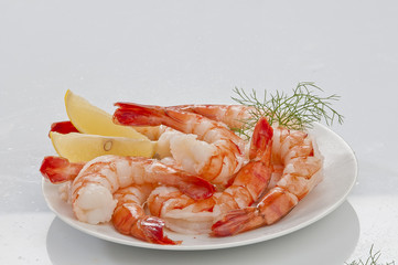 Steamed Jumbo headless shrimps with deli leaves and Lemon on white plate on white background 
