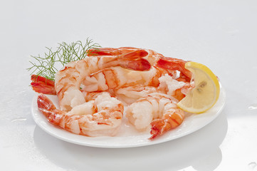 Steamed Jumbo headless shrimps with deli leaves and Lemon on white plate on white background 