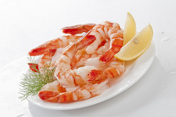 Steamed Jumbo headless shrimps with deli leaves and Lemon on white plate on white background 