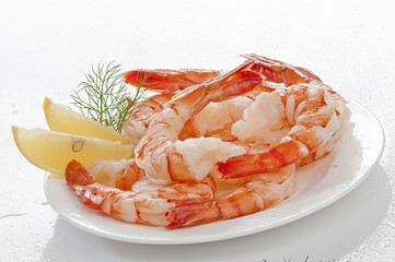 Steamed Jumbo headless shrimps with deli leaves and Lemon on white plate on white background 