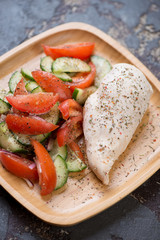 Bamboo tray with boiled chicken breast and fresh vegetables, vertical shot