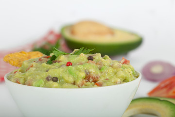 Guacamole with avocado, lime, tomato, and cilantro with tortilla chips.