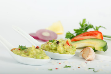 Fresh avocado dip guacamole in white spoons with ingrediants
