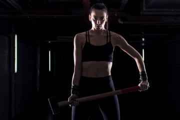 Fototapeta na wymiar Strong girl with hammer on her hands in gym