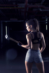 Strong girl with hammer on her hands exercise in gym