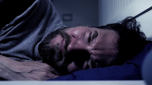 Desperate man suffering at night lying in bed slow motion