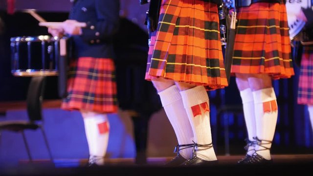 Traditional scottish band musicians singing with bagpipes on the stage