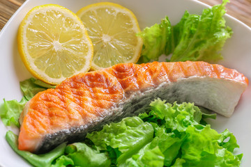 Plate with tasty grilled salmon and lemon slices, closeup