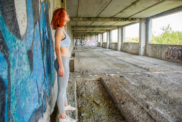 Fitness girl on the background wall with graffiti by an unknown author