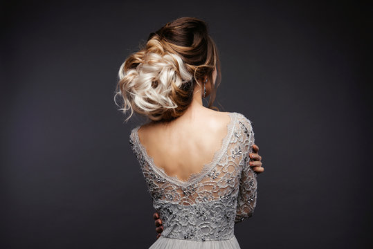 Studio Portrait of a Beautiful Bride Model in a Light Gray Wedding Dress with Elegant  Hairstyle and Pink Lips at Gray Background