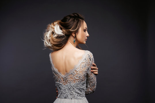 Studio Portrait of a Beautiful Bride Model in a Light Gray Wedding Dress with Elegant  Hairstyle and Pink Lips at Gray Background