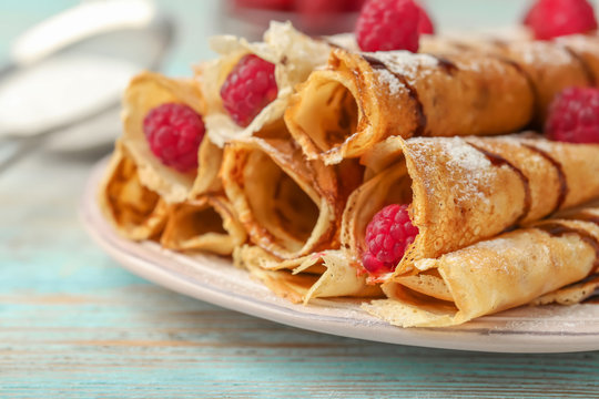 Plate with delicious rolled pancakes and berries on table, closeup